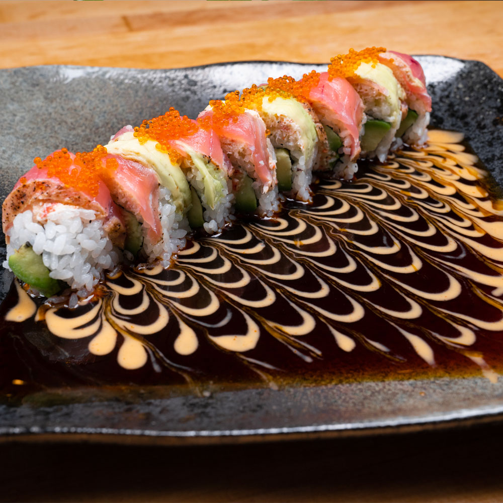 Ocean Roll — a sushi roll topped with snow crab, seared tuna, and avocado, drizzled with sauce.
