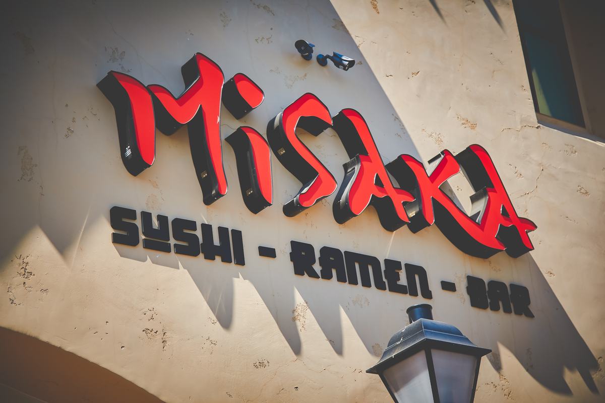 The front of Misaka Sushi — look for the red neon sign reading Sushi, Ramen, Bar above the entrance.