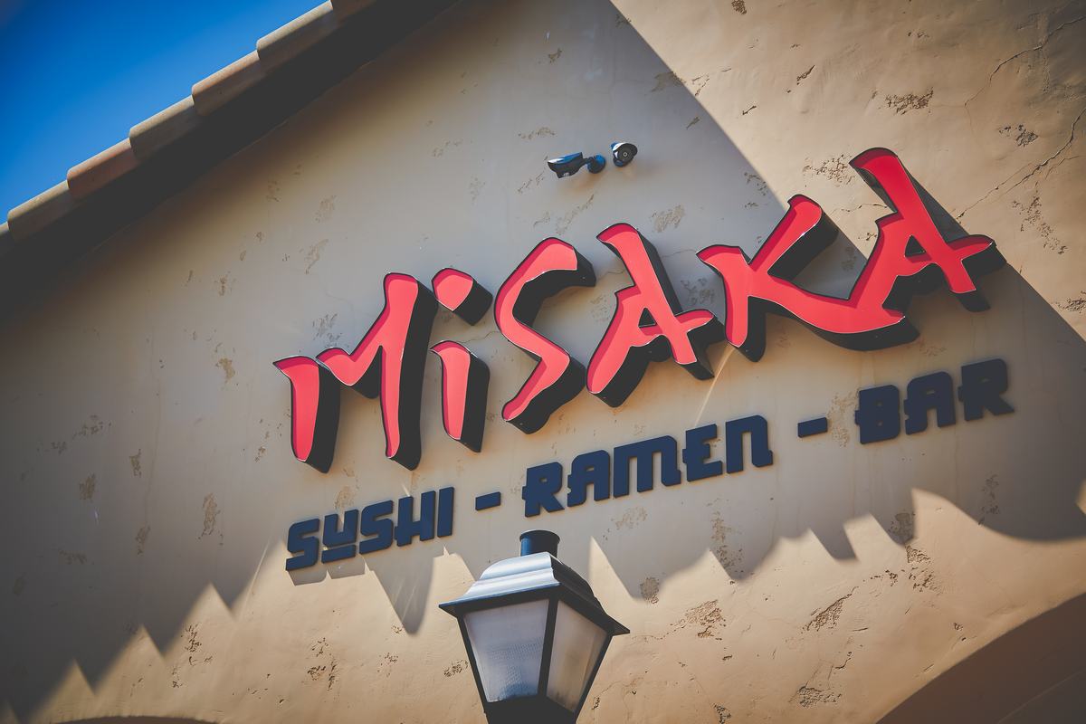 Misaka's red neon sign reading Sushi, Ramen, Bar above the front entrance.