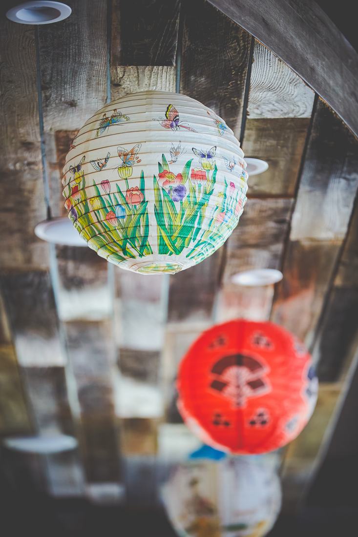 Painted paper lanterns hanging in front of a bamboo screen.